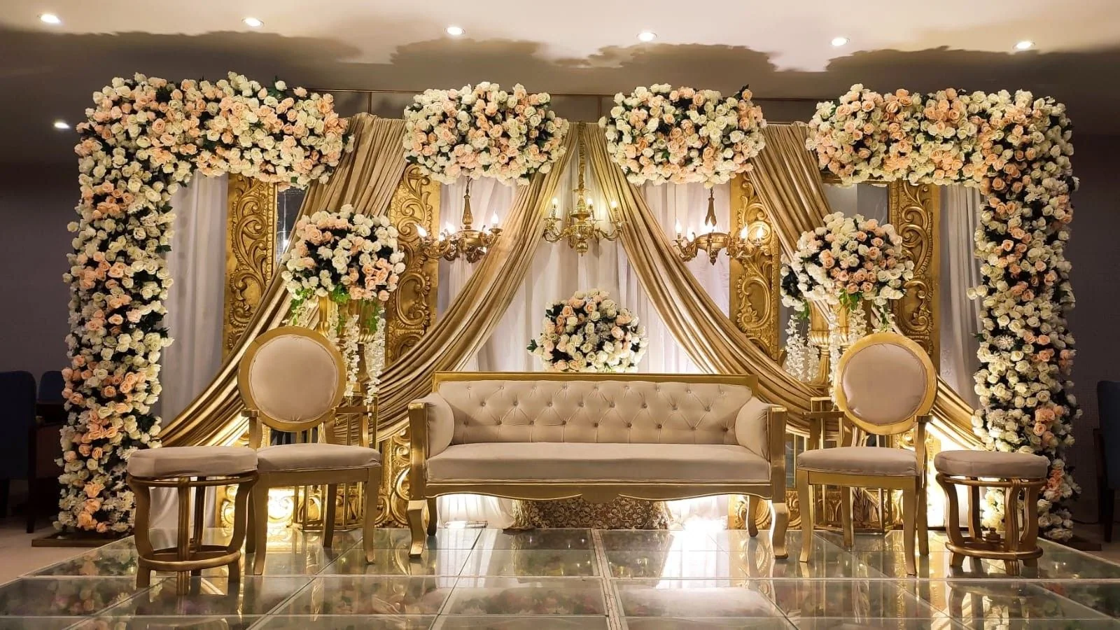 Gold and ivory floral stage decoration with elegant wedding seating